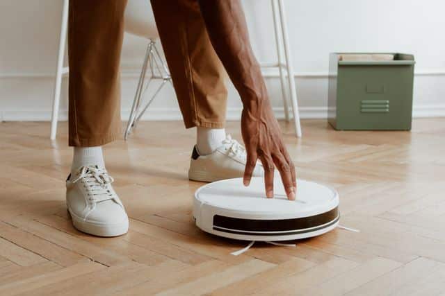 un homme qui touche un aspirateur robot
