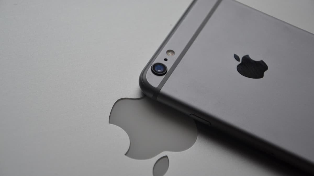 un iphone est posé face contre une tablette représentant le logo d'une pomme croquée